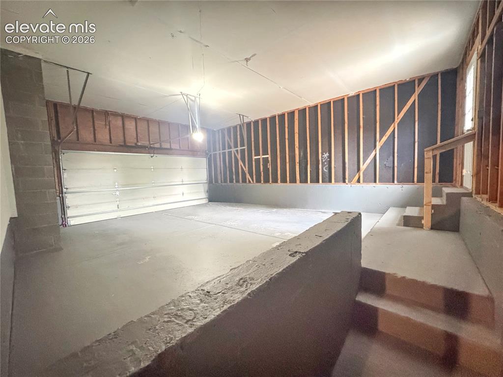 Image 32 of 42: Multi-car garage featuring a sectional metal overhead door, concrete floori