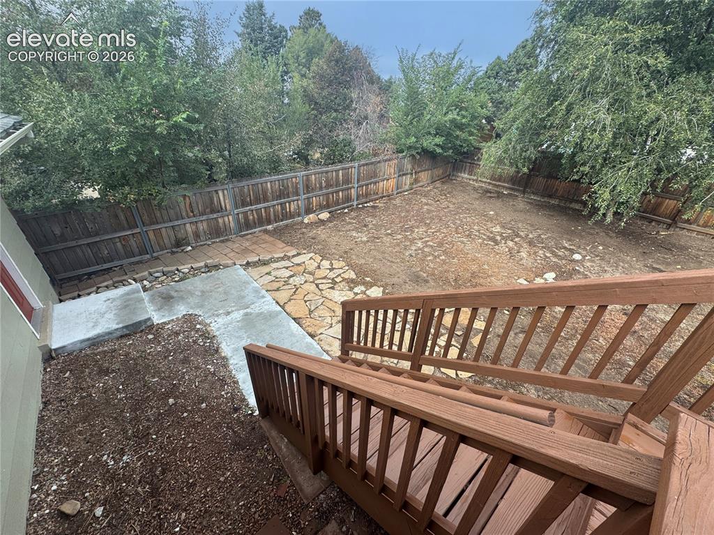 Image 35 of 42: Rear exterior space featuring a wood-railed staircase, concrete patio, ston
