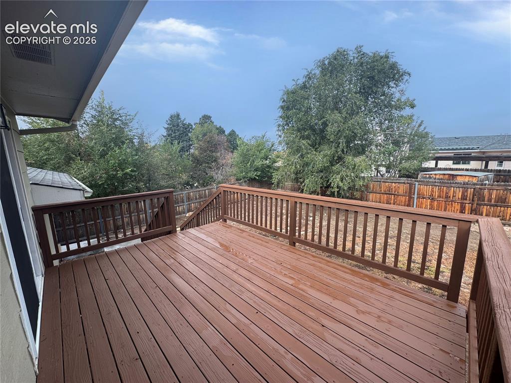 Image 5 of 42: Elevated wood deck featuring stained wooden railings and mature trees