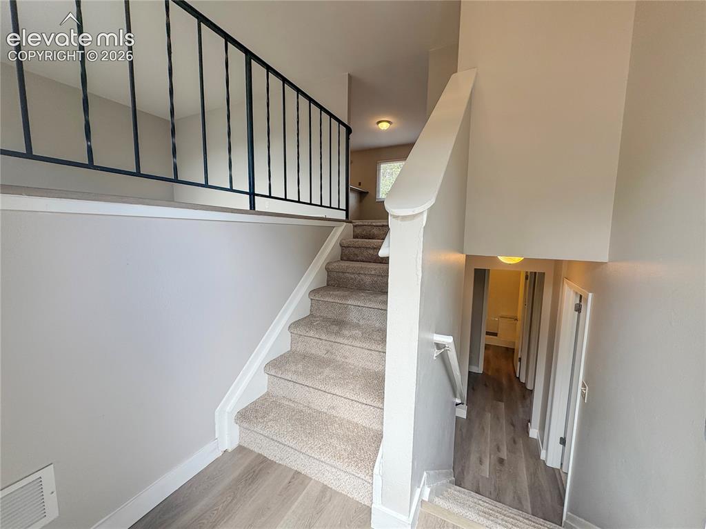 Image 6 of 42: Staircase featuring carpeted treads, metal balustrades, wood-finish floorin