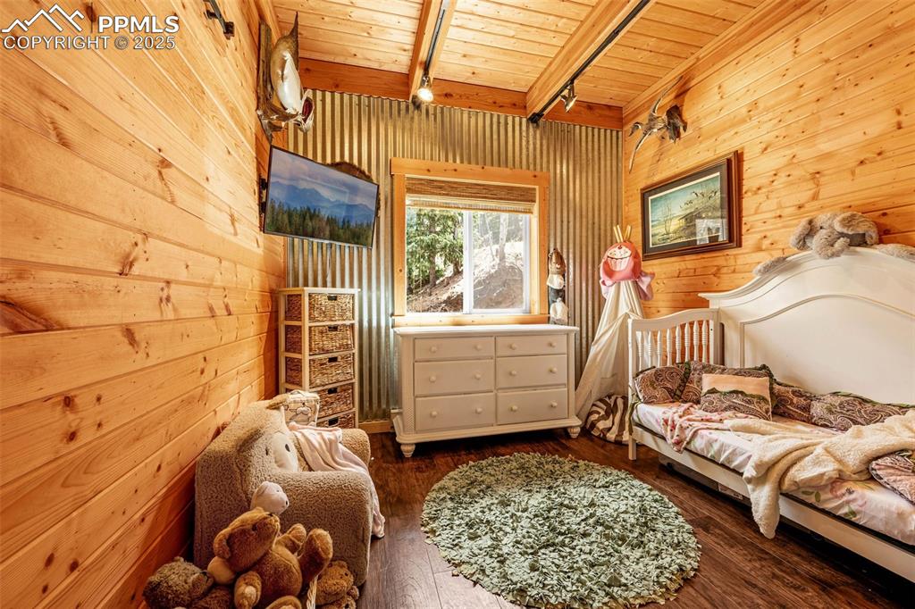Image 12 of 45: Bedroom with wood walls, wood ceiling, beam ceiling, and wood-type flooring