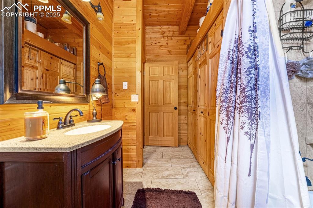 Image 14 of 45: Bathroom with wooden walls, vanity, and wood ceiling