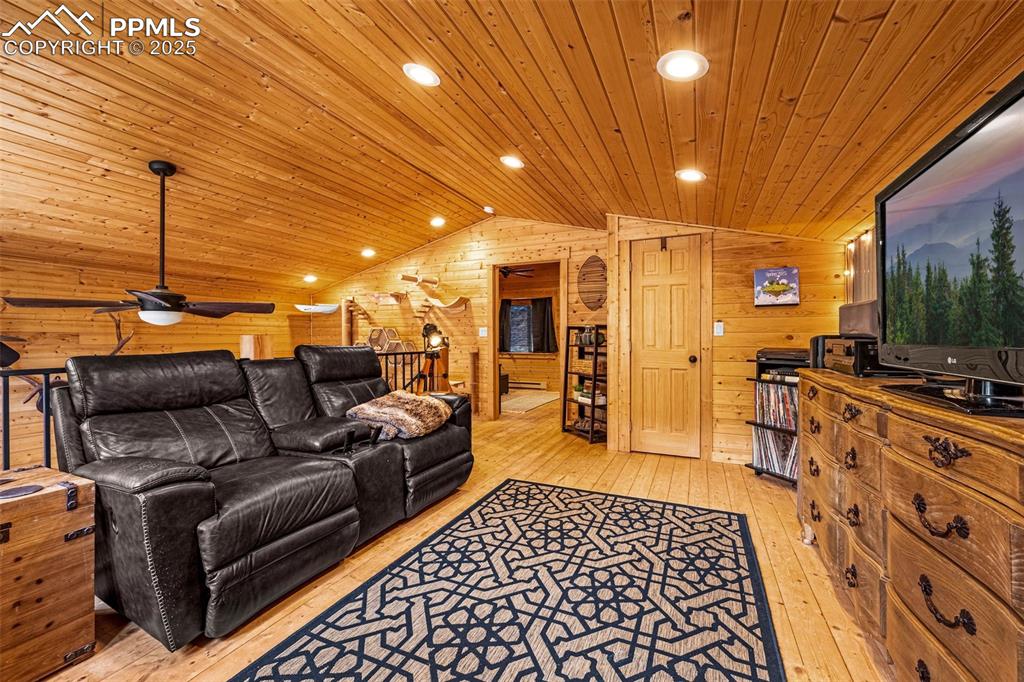 Image 16 of 45: Living room featuring vaulted ceiling, light wood-style floors, wooden wall