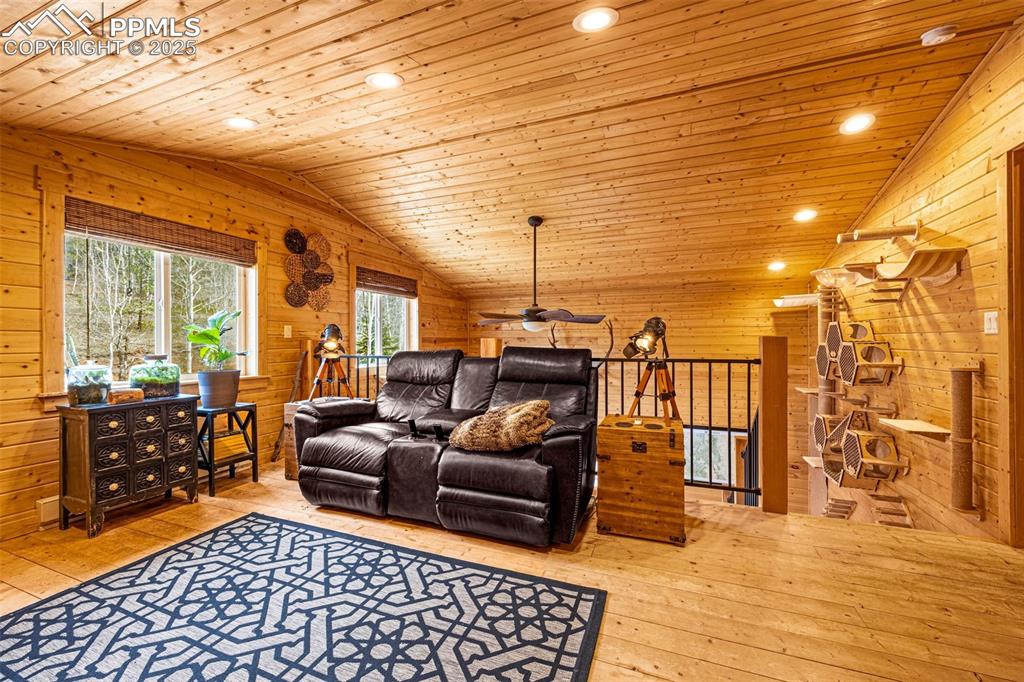 Image 17 of 45: Living room with lofted ceiling, wooden ceiling, wooden walls, wood-type fl