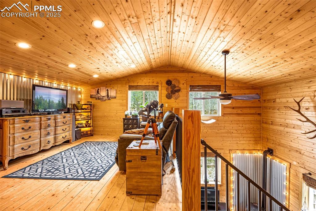 Image 18 of 45: Living area with wooden ceiling, lofted ceiling, wood walls, hardwood / woo