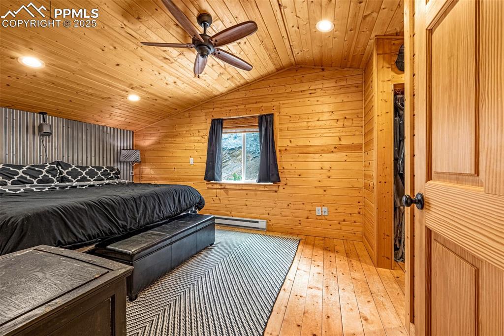 Image 20 of 45: Bedroom with a baseboard radiator, lofted ceiling, wooden walls, wood-type 