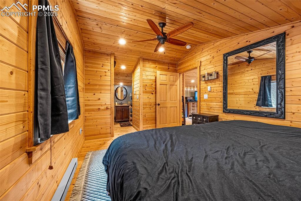 Image 21 of 45: Bedroom with wooden walls, wooden ceiling, wood finished floors, and vaulte