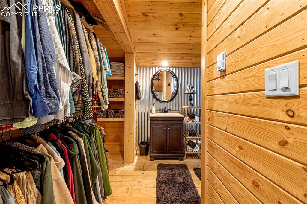 Image 22 of 45: Walk in closet with light wood finished floors and a sink