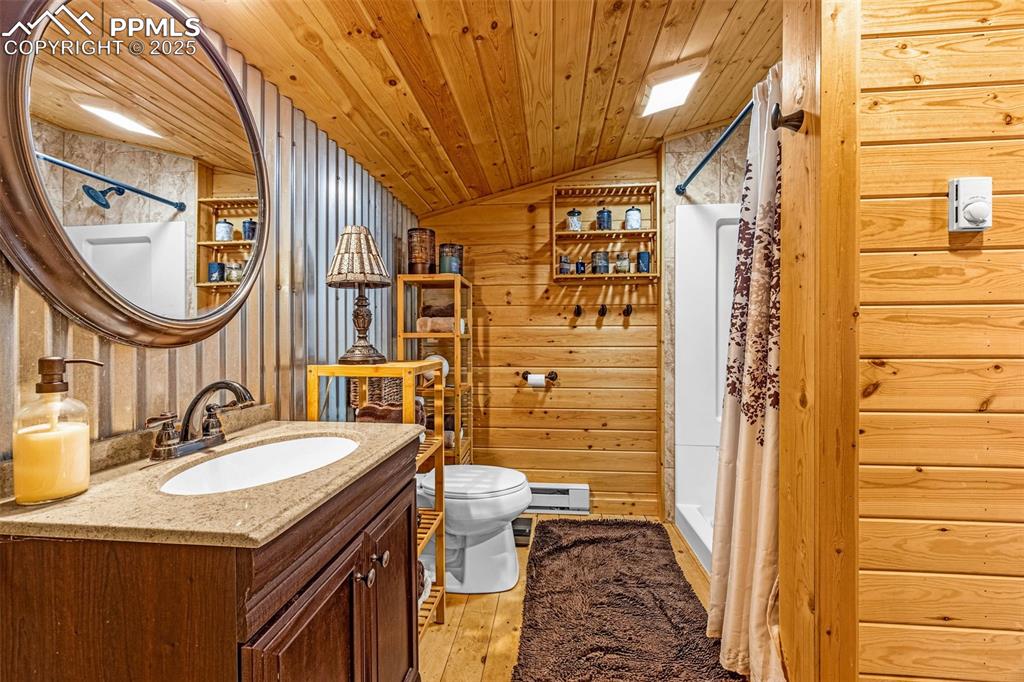 Image 23 of 45: Full bath with a shower stall, lofted ceiling, hardwood / wood-style floors