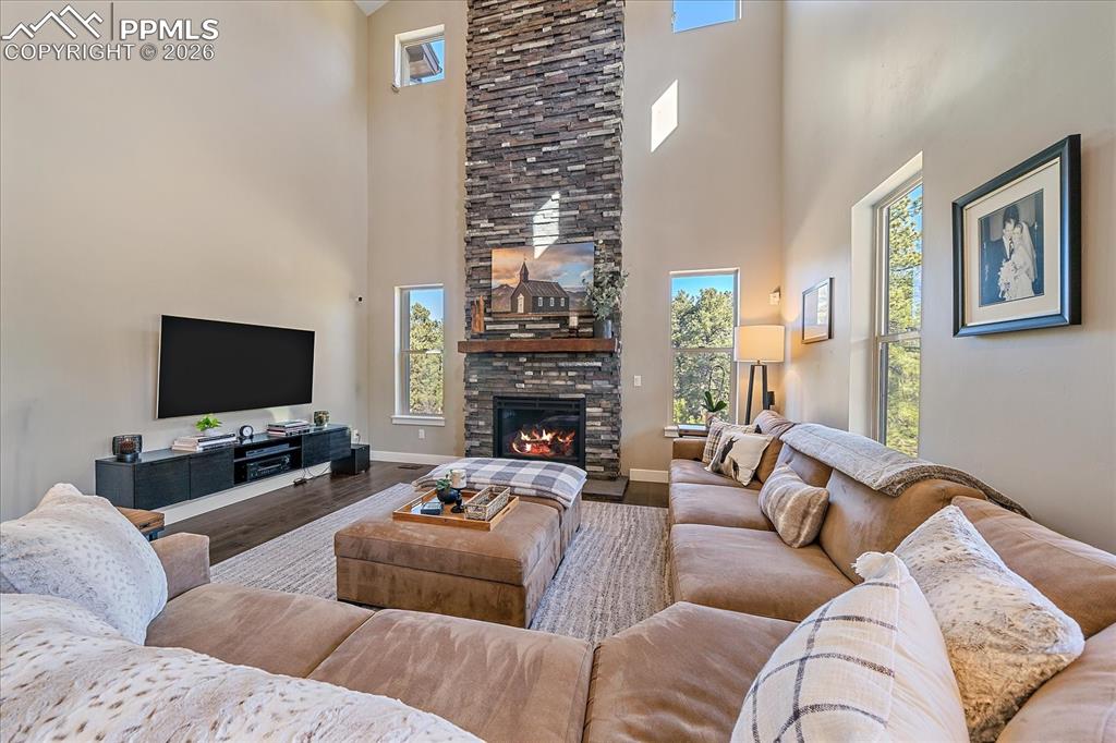 Image 11 of 50: The two story great room is anchored by a floor to ceiling fireplace and ha