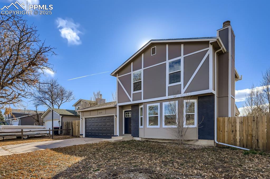 Caption: View of front of home with a chimney, concrete driveway, and a garage