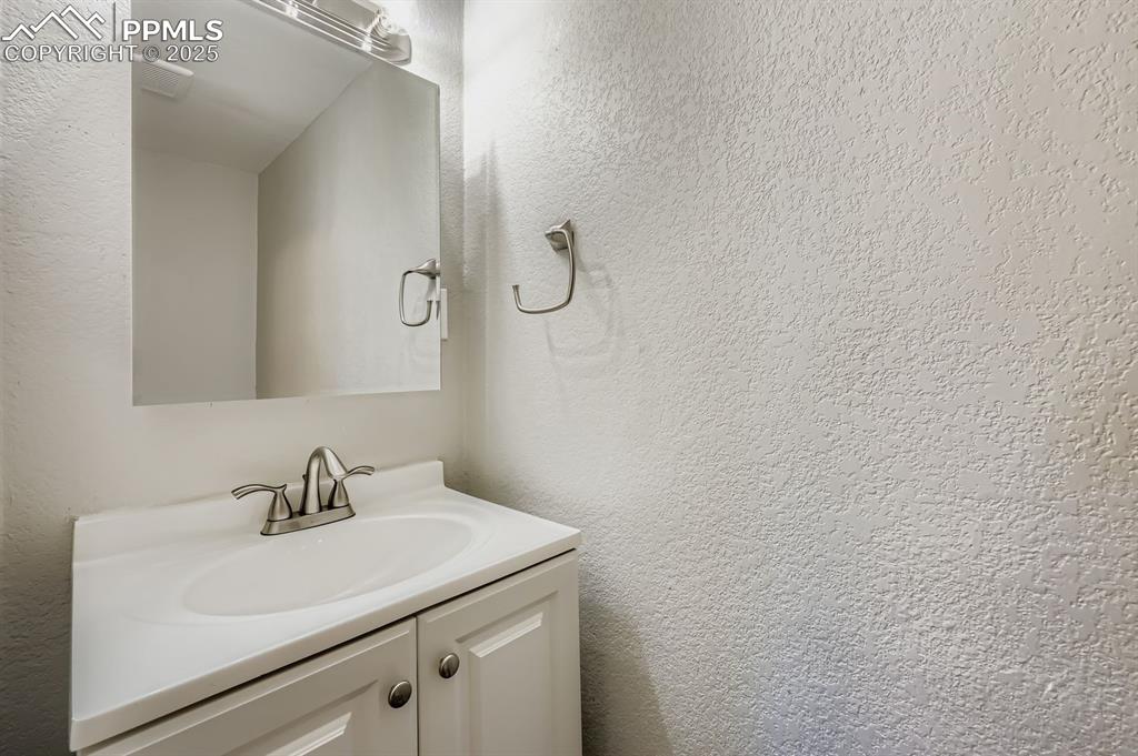 Image 11 of 28: Bathroom featuring a textured wall and vanity