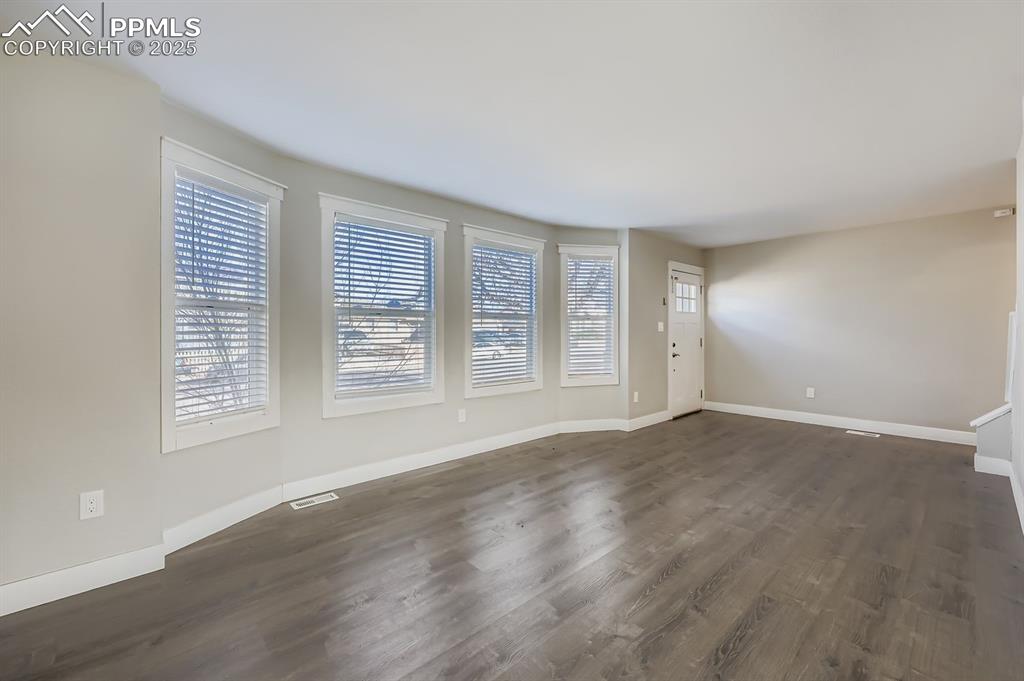 Image 4 of 28: Unfurnished living room featuring dark wood finished floors and healthy amo