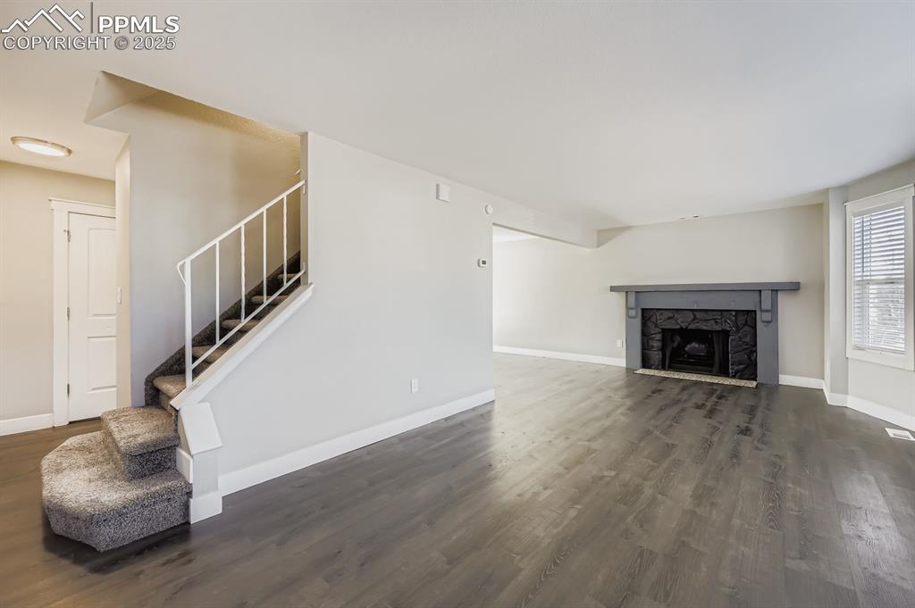 Image 5 of 28: Unfurnished living room featuring a fireplace, luxury flooring, and stairs 