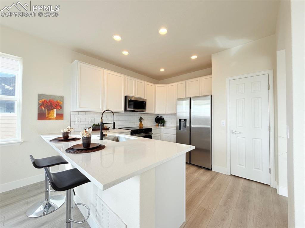 Image 12 of 49: Kitchen featuring appliances with stainless steel finishes, decorative back