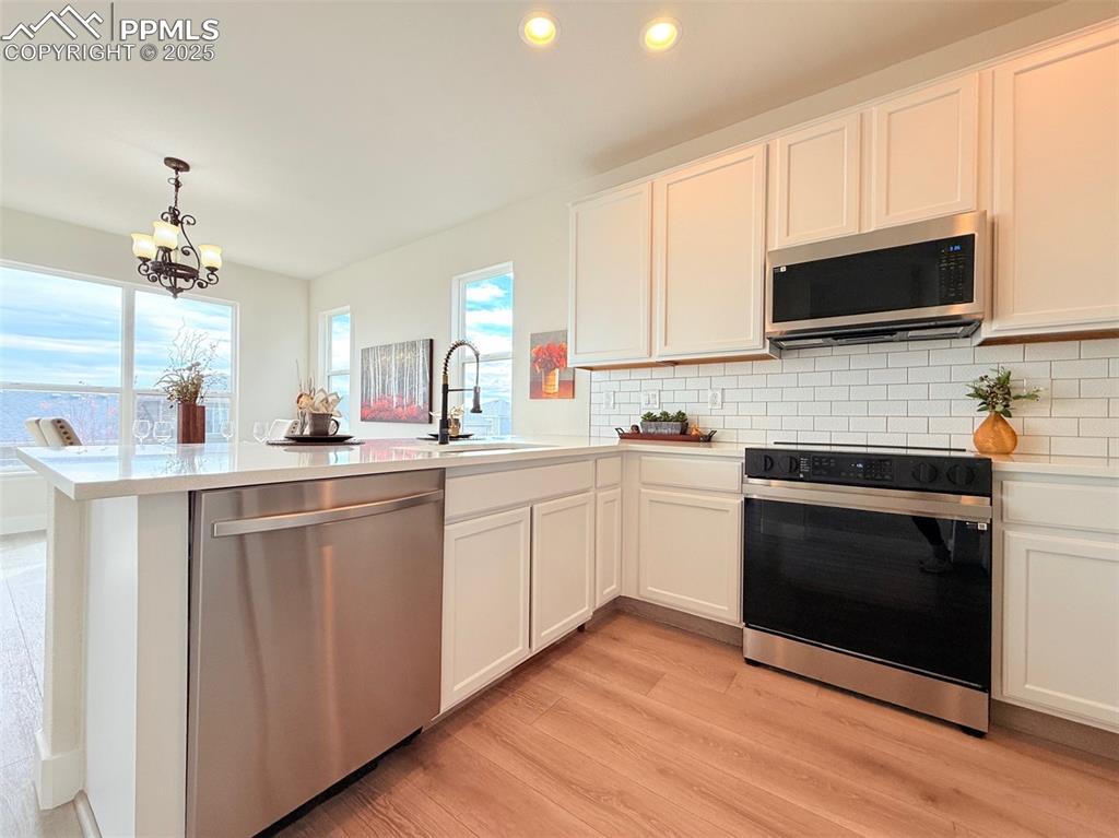 Image 14 of 49: Kitchen with appliances with stainless steel finishes, a peninsula, backspl