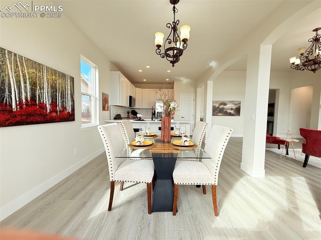 Image 18 of 49: Dining space featuring a chandelier, arched walkways, light wood finished f
