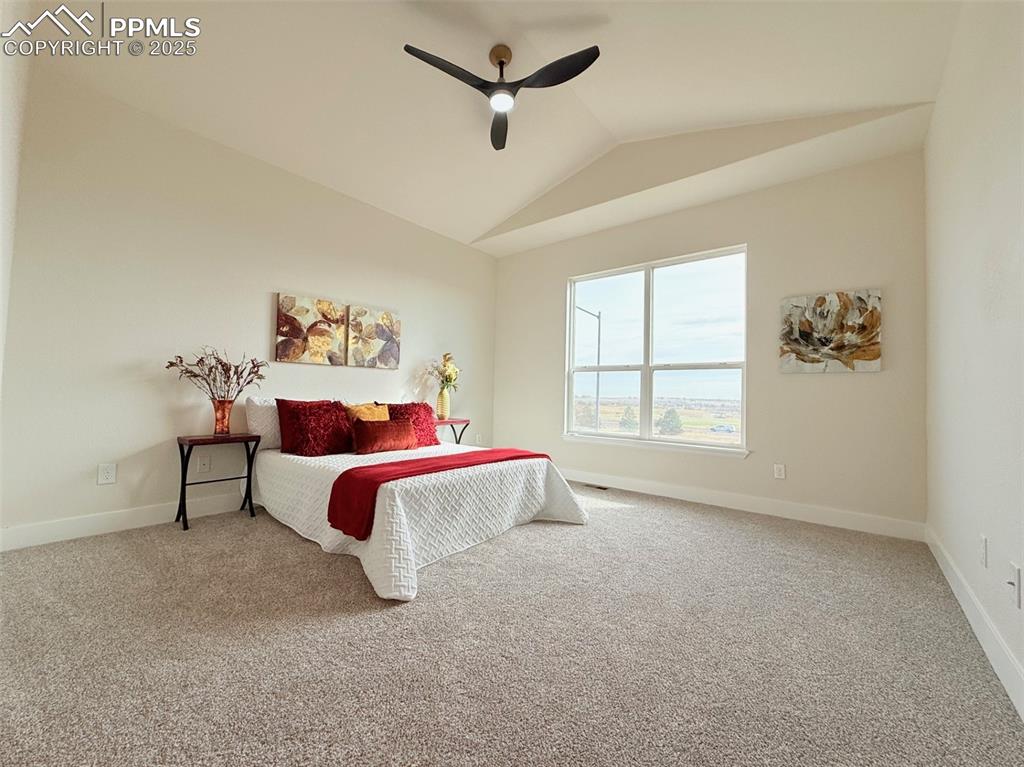 Image 20 of 49: Bedroom with vaulted ceiling, light colored carpet, and ceiling fan