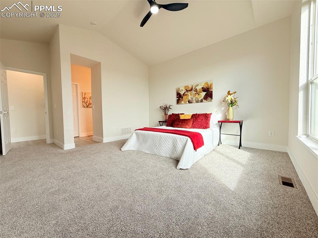 Image 21 of 49: Bedroom with light colored carpet, lofted ceiling, and a ceiling fan