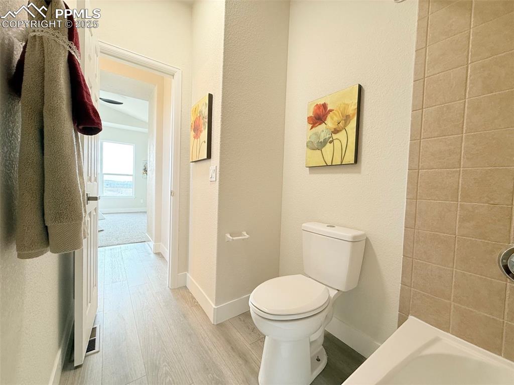 Image 24 of 49: Full bath featuring light wood-type flooring, a textured wall, and a tub to