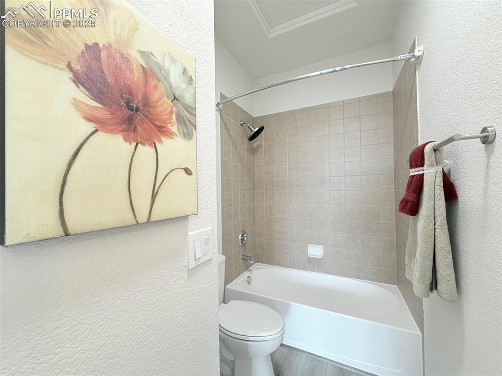Image 25 of 49: Full bath featuring a textured wall, shower / bath combination, and wood fi