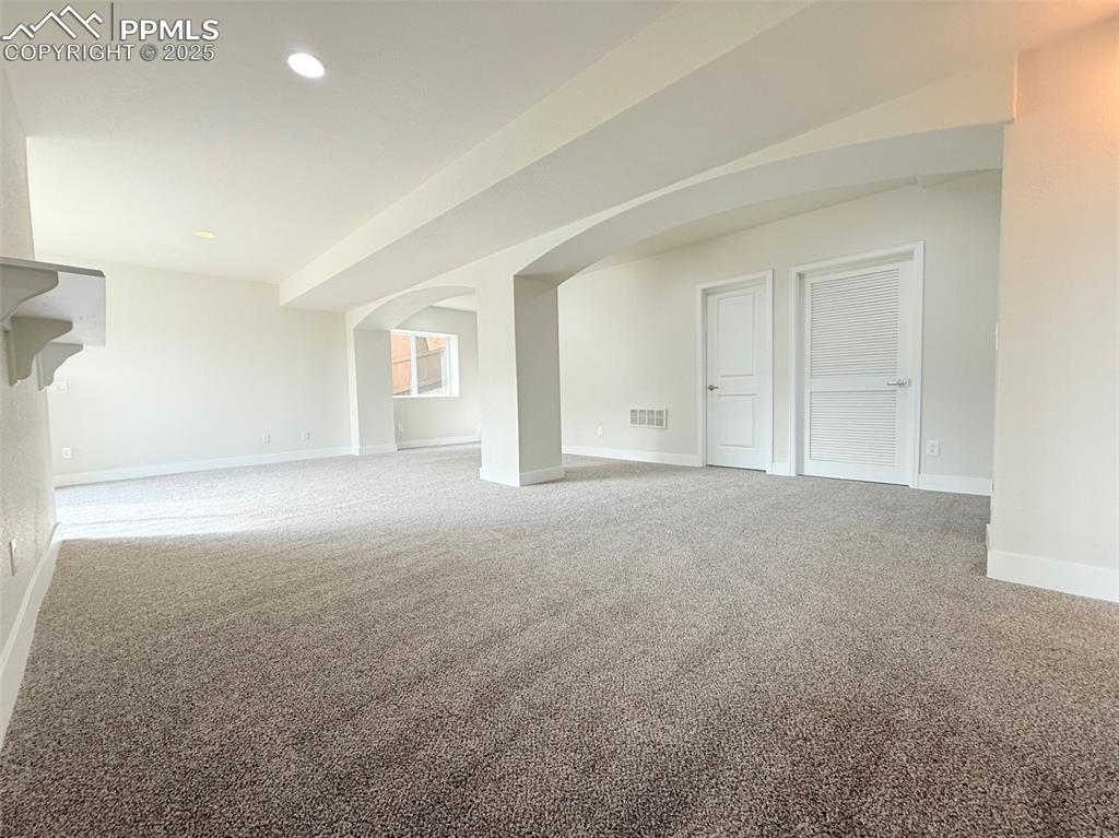 Image 32 of 49: Basement with arched walkways, carpet, and recessed lighting