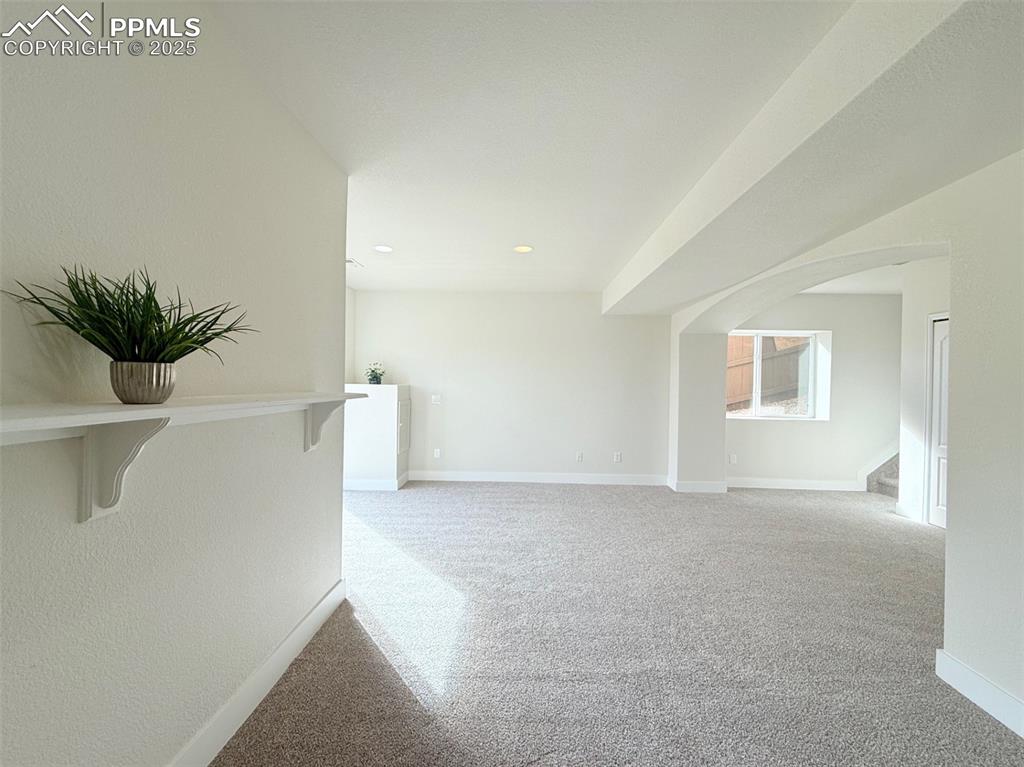 Image 33 of 49: Unfurnished room with arched walkways, light carpet, and recessed lighting