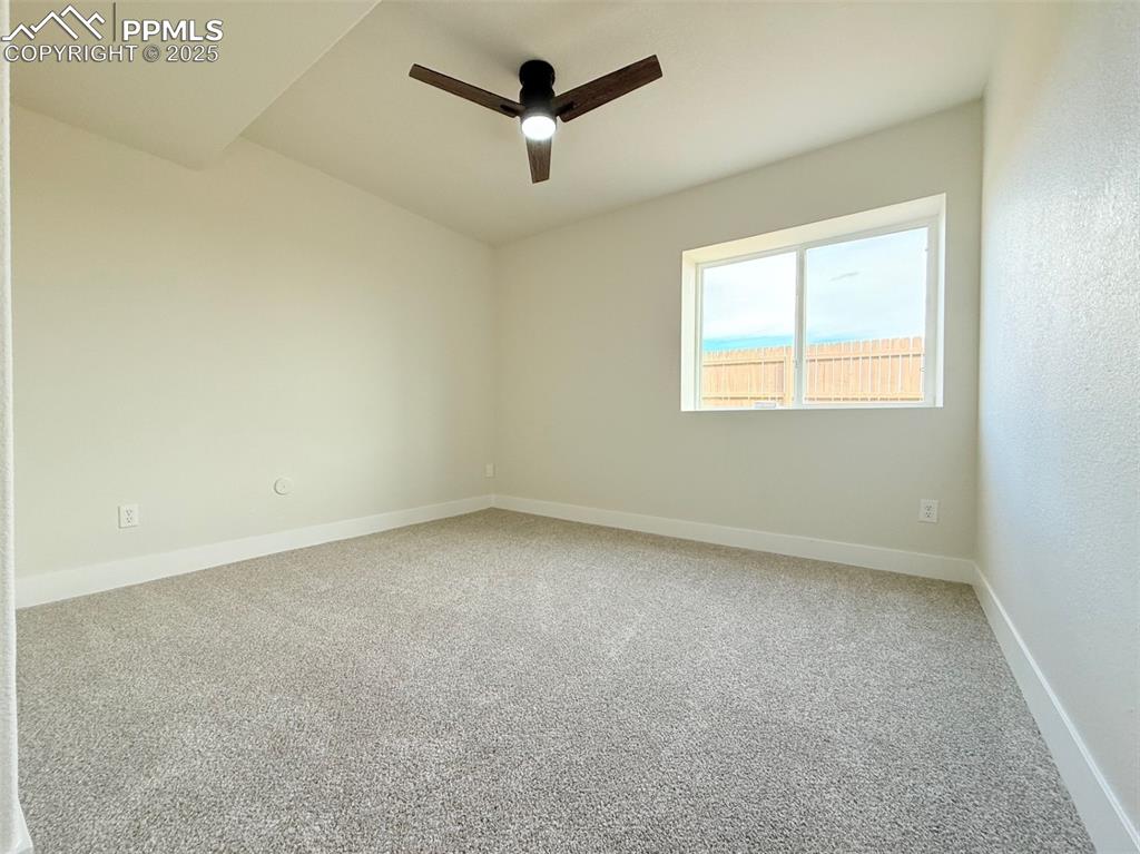 Image 35 of 49: Empty room with light colored carpet and a ceiling fan