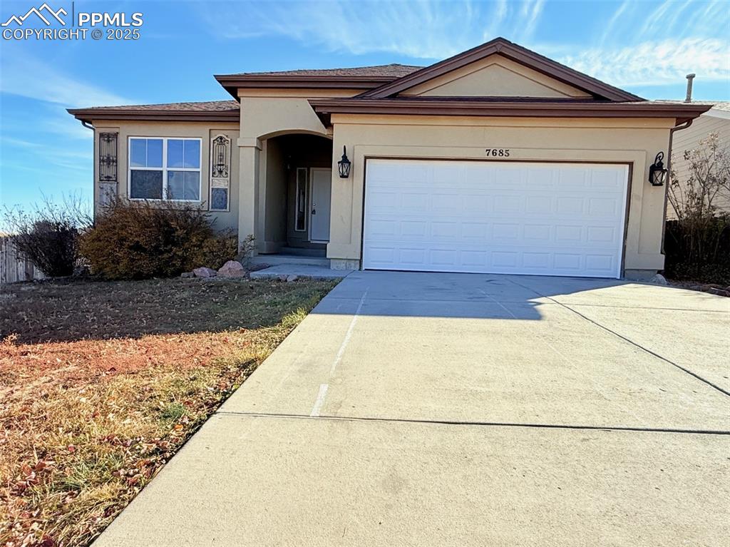 Image 49 of 49: Ranch-style house featuring concrete driveway, a garage, and stucco siding