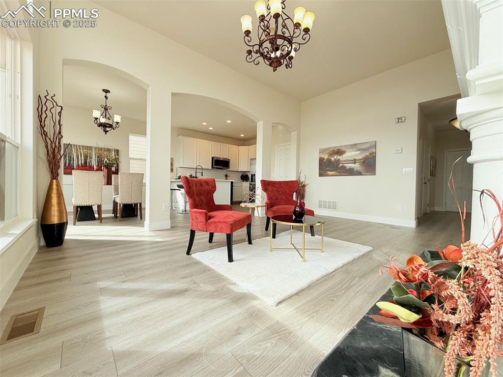 Image 8 of 49: Sitting room with a chandelier, arched walkways, light wood-type flooring, 