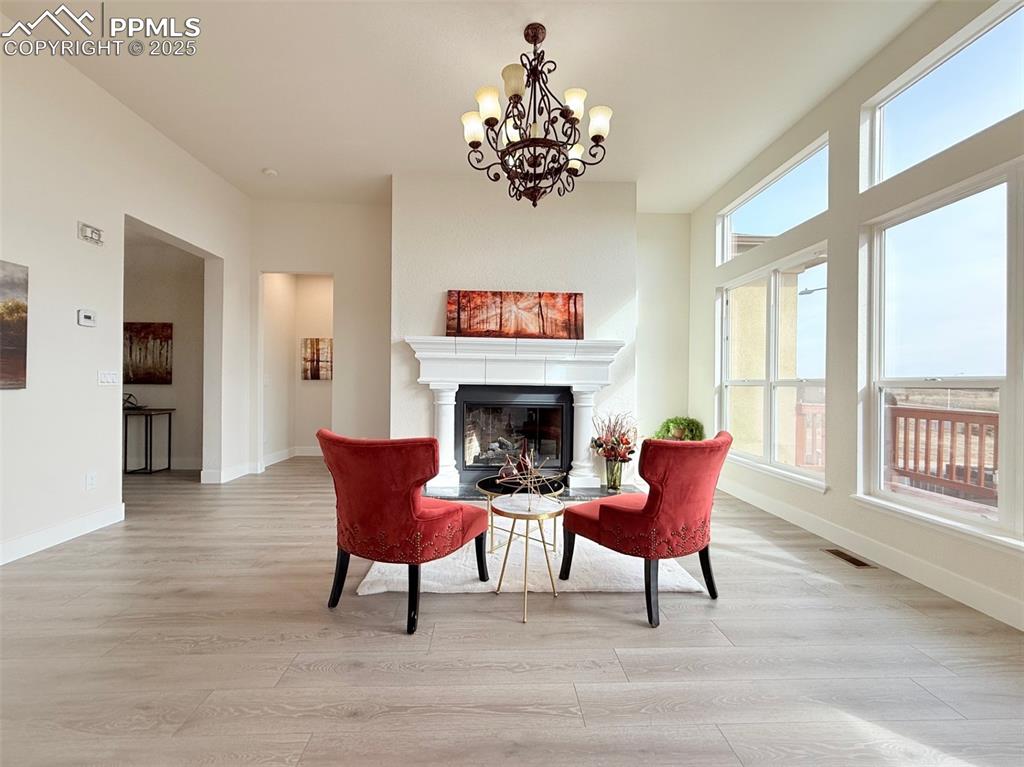 Image 9 of 49: Living area with light wood-style flooring, a glass covered fireplace, and 