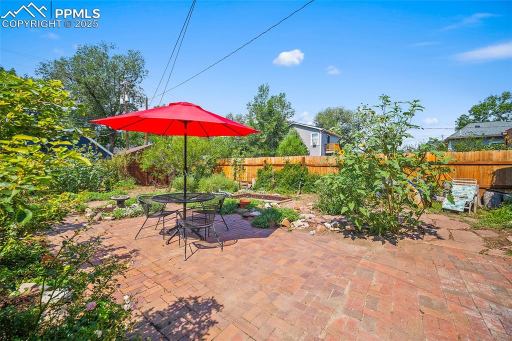 Image 36 of 39: Brick patio surrounded by wildflowers and fruit trees. 