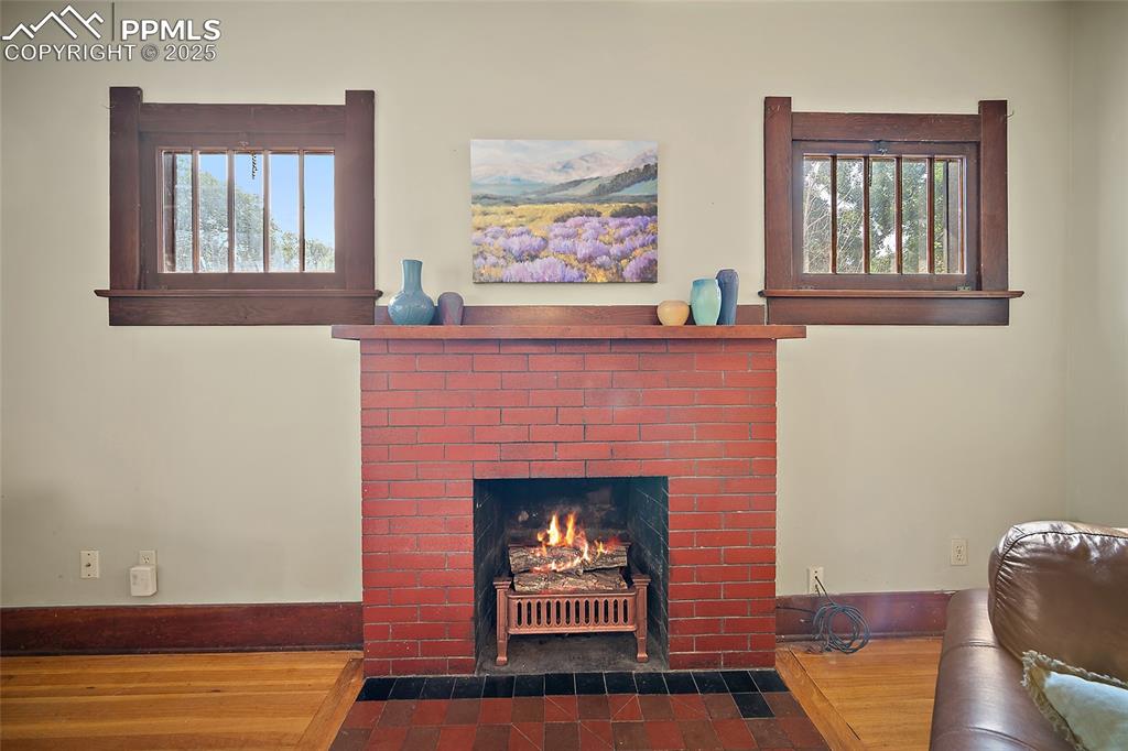 Image 7 of 39: Original fireplace with brick surround and tile hearth. 