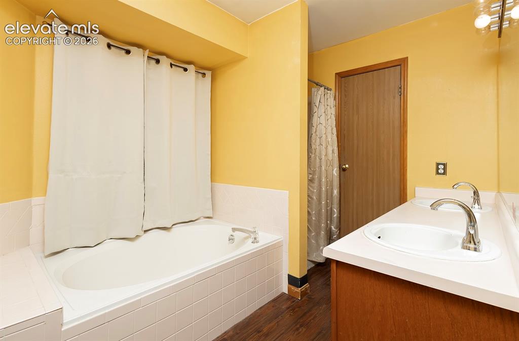 Image 12 of 32: Bathroom featuring a spacious built-in tub with white tile surround, a doub