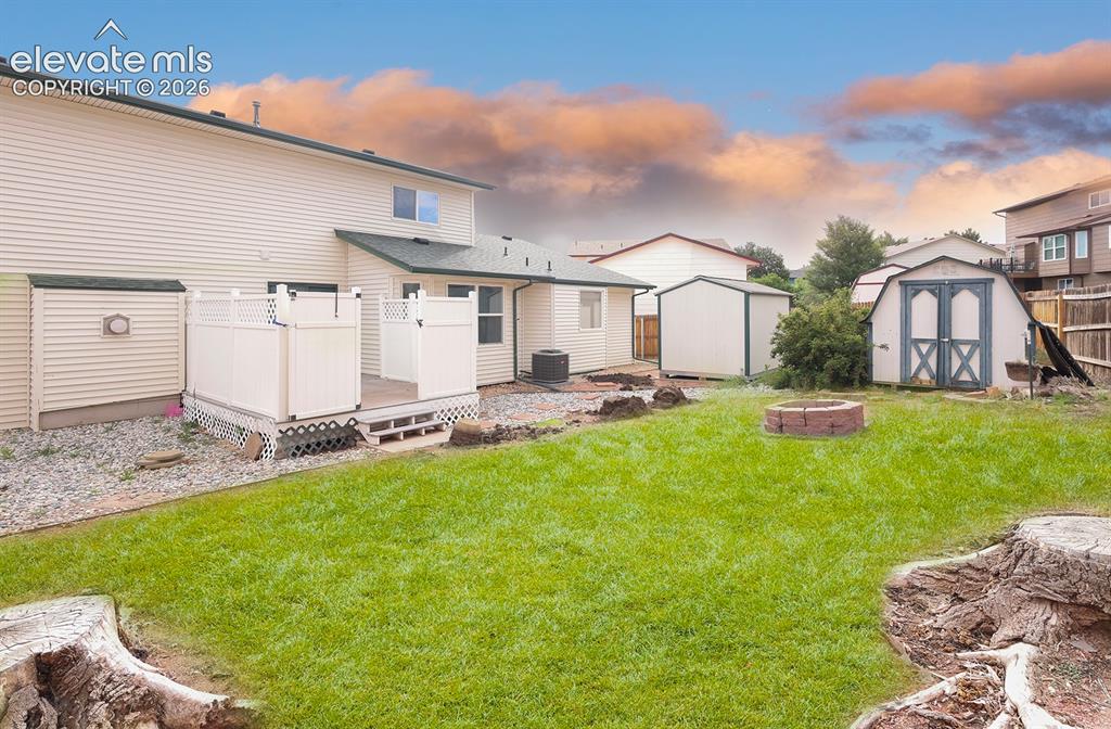 Image 17 of 32: Expansive backyard featuring a manicured lawn, a compact deck with privacy