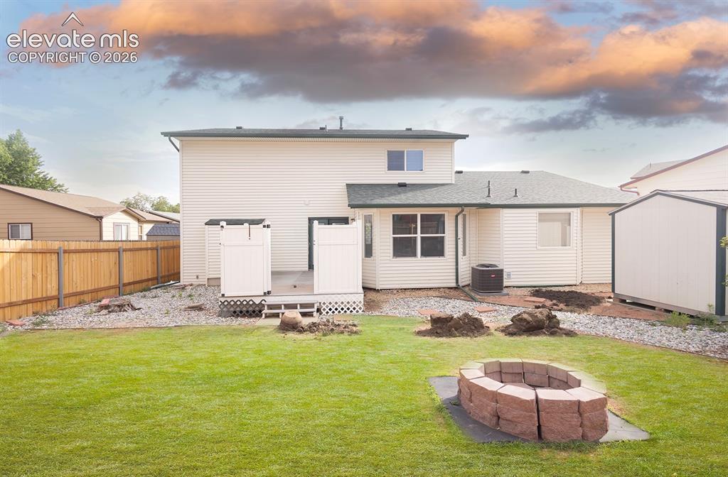 Image 18 of 32: Expansive backyard featuring a green lawn, wood privacy fencing, and a buil