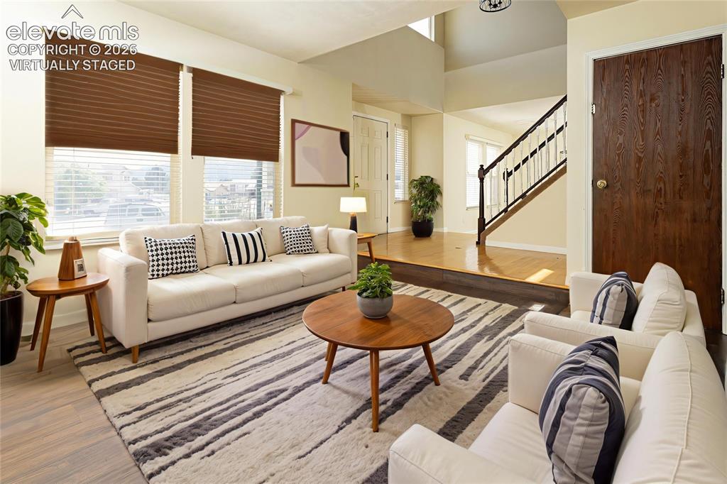 Image 2 of 32: Open living area featuring wood-finish flooring, large windows with blinds,