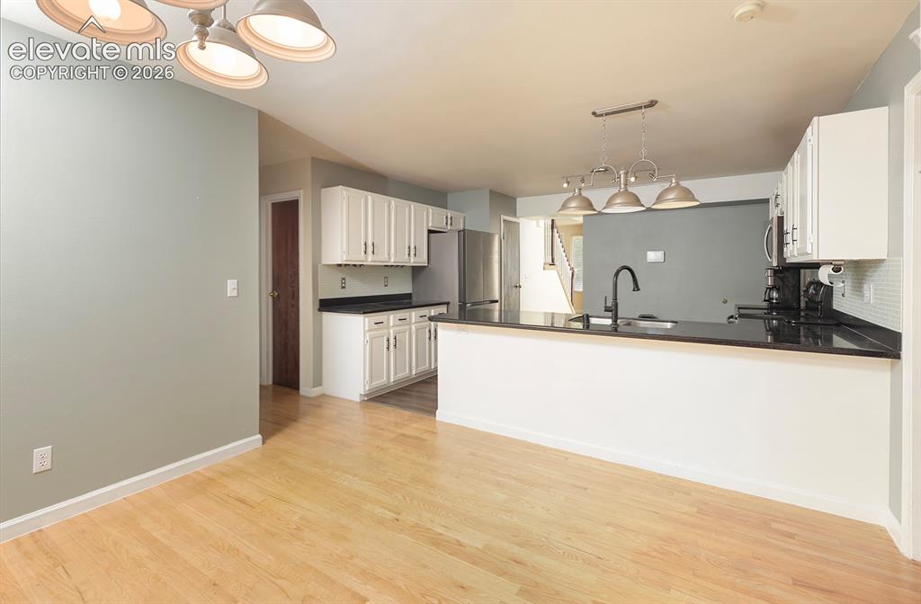 Image 26 of 32: Open-concept kitchen and dining area featuring light wood-finish flooring,