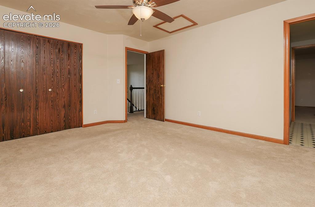 Image 30 of 32: Carpeted room featuring a ceiling fan, two wood-grain bi-fold closet doors,