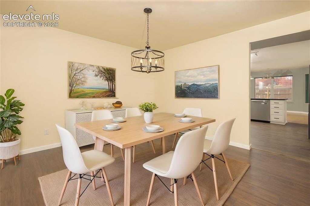 Image 4 of 32: Dining area featuring warm-toned walls, dark wood-finish flooring, and a co