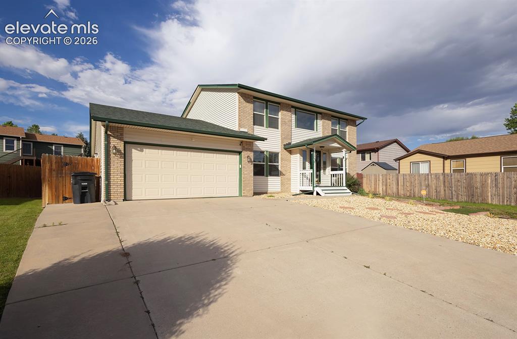 Image 7 of 32: Two-story residence featuring a brick and siding exterior, green shingle ro