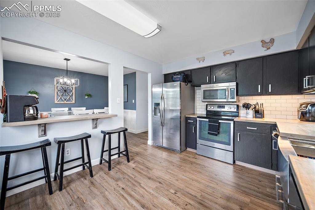 Image 29 of 49: Kitchen with dark cabinetry, stainless steel appliances, tasteful backsplas