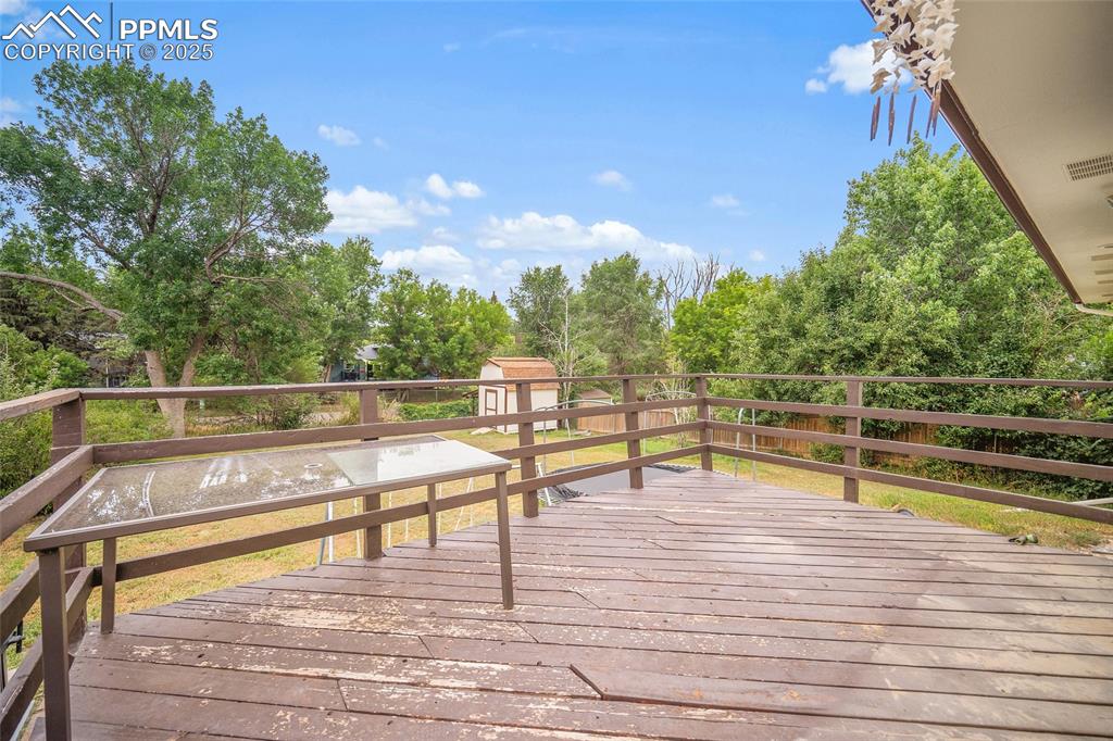 Image 31 of 49: Deck with view of scattered trees and a storage shed