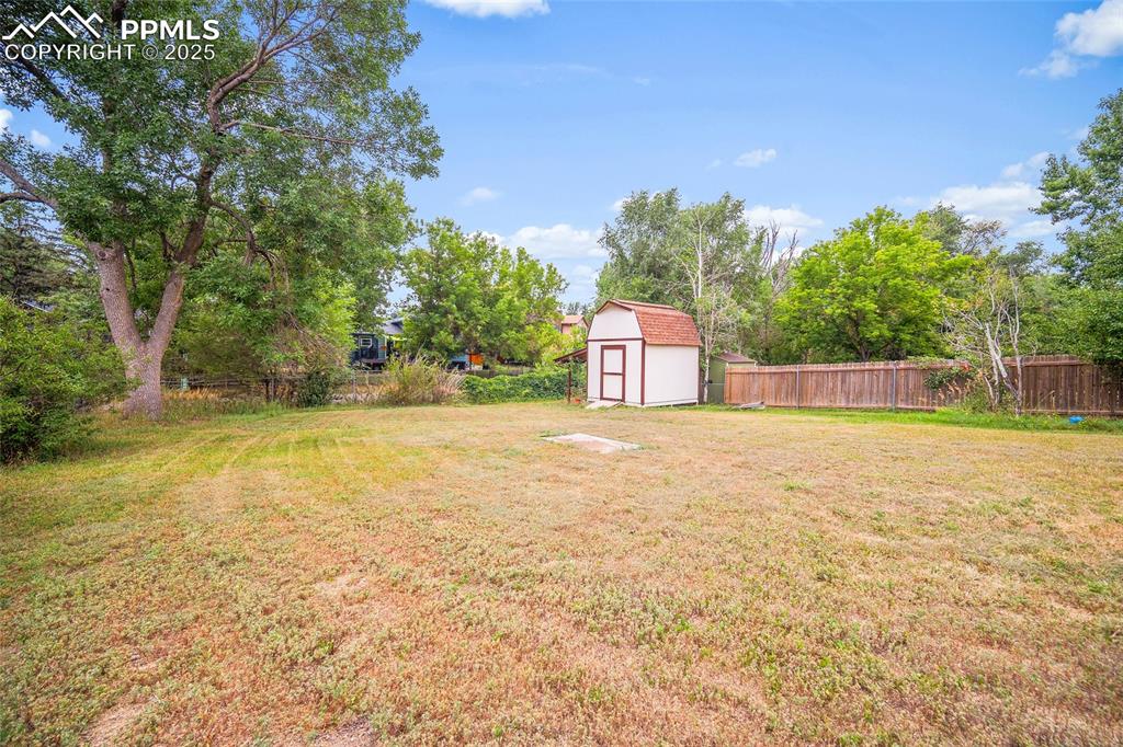 Image 32 of 49: View of yard featuring a storage shed and view of scattered trees