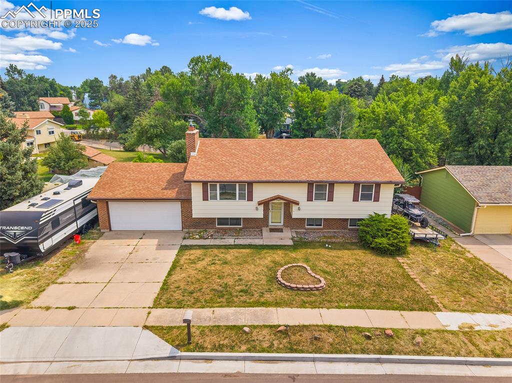 Image 36 of 49: Split foyer home with brick siding, a chimney, driveway, a front yard, and 