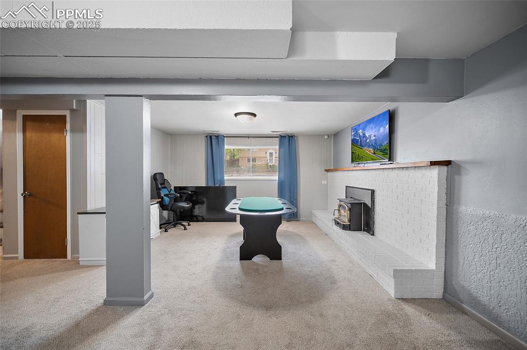 Image 7 of 49: Rec room featuring carpet floors, a wood stove, and an office area