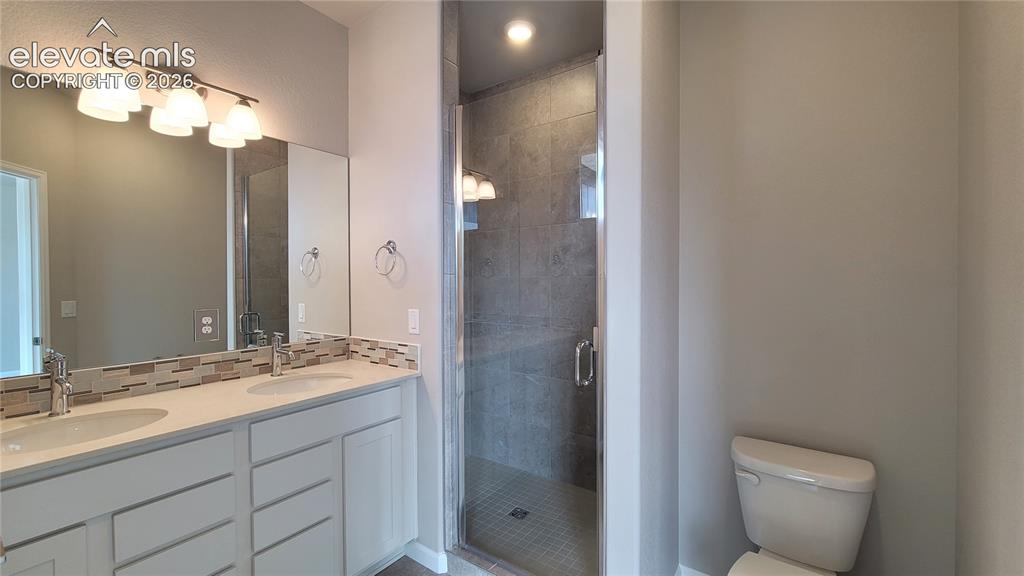 Image 21 of 28: Primary Bathroom with quartz countertop with double vanity, shower, and til