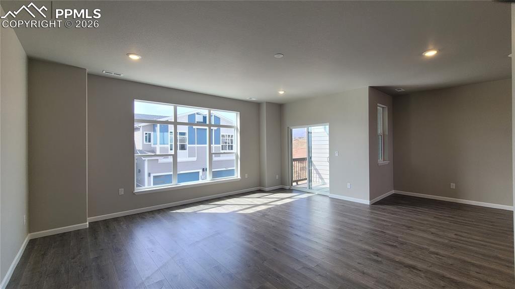 Image 8 of 25: Living room with LVP flooring, LED lighting, Walk-Out to Composite Deck, an
