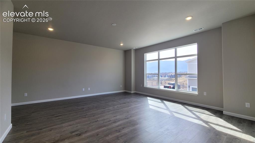 Image 8 of 28: Living room with LVP flooring, LED lighting, Walk-Out to Composite Deck, an