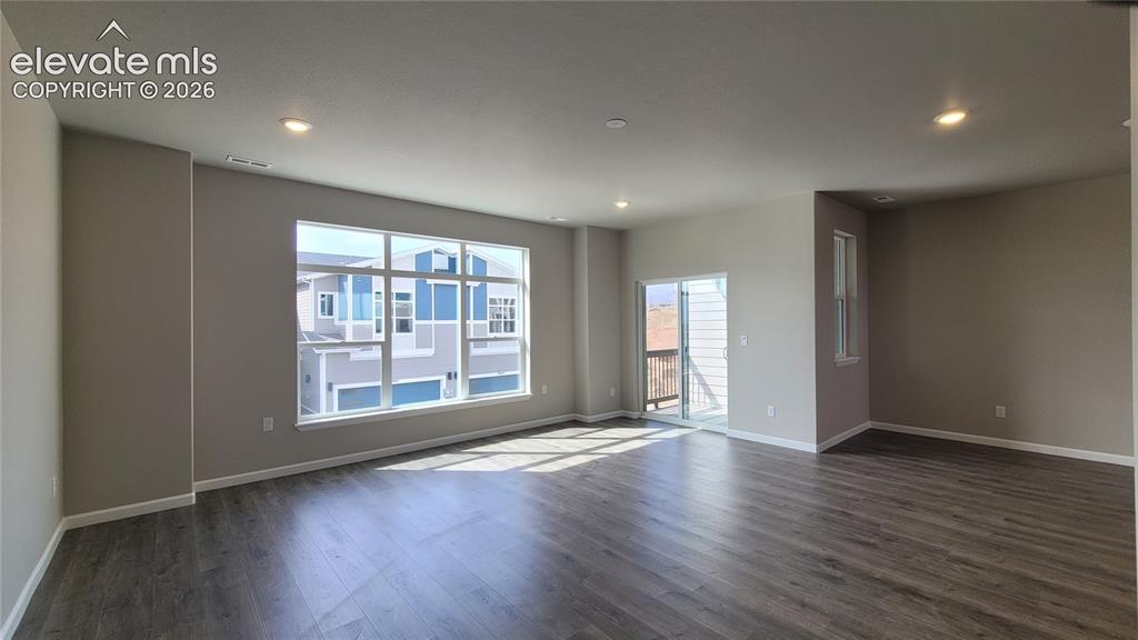 Image 9 of 28: Living room with LVP flooring, LED lighting, Walk-Out to Composite Deck, an